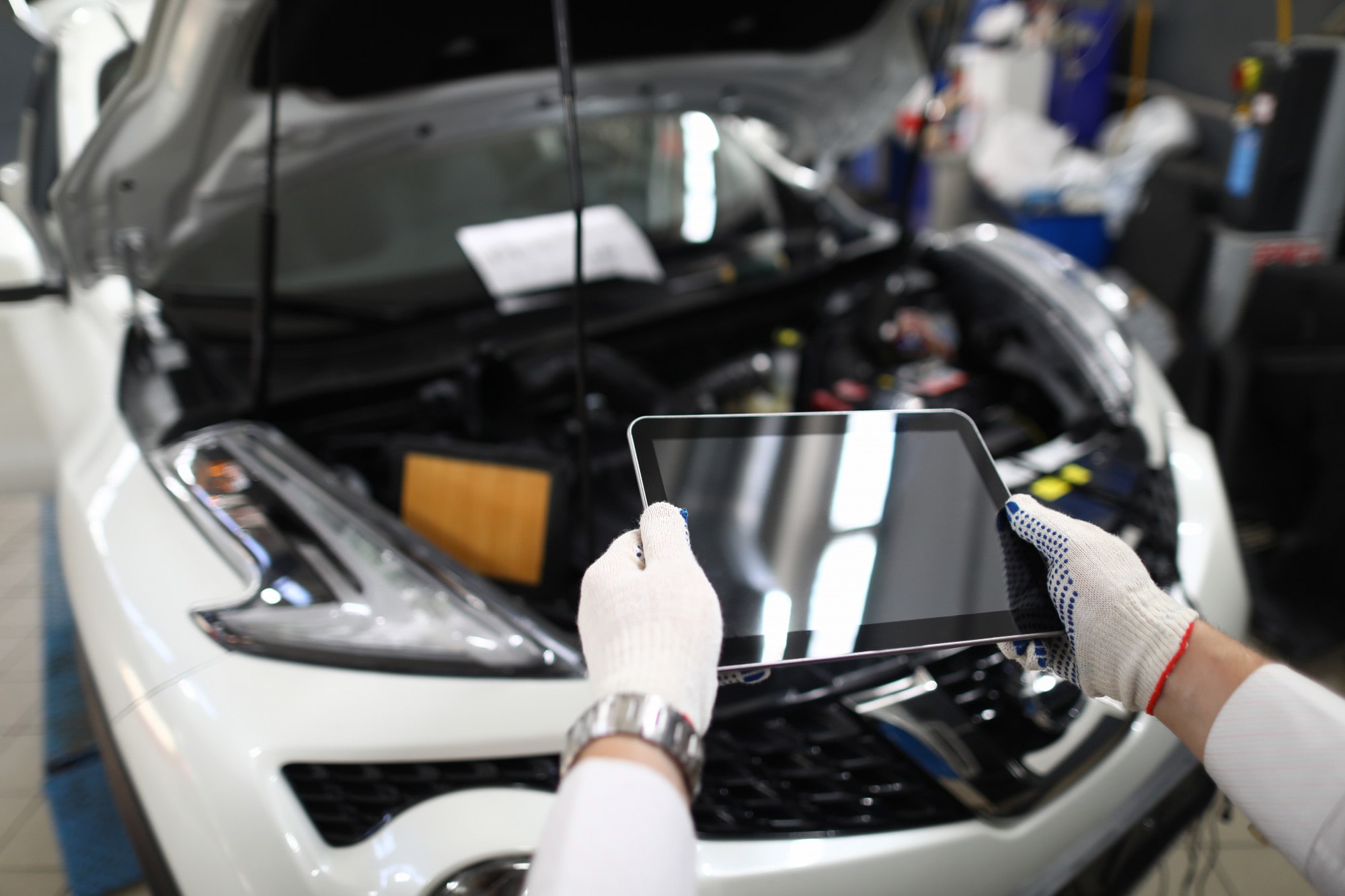 Auto mit offener Motorhaube, davor eine Person mit Tablet, Quelle: Freepik